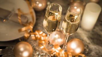 Two champagne flutes on a table with gold ribbons and ornaments.