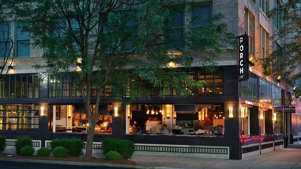 A modern building with a restaurant on the ground floor, featuring large windows and outdoor seating. - Louisville Marriott Downtown (Louisville)