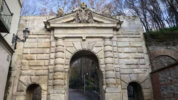 Un arco de piedra con un escudo de armas, flanqueado por dos arcos más pequeños y un farol a la izquierda.