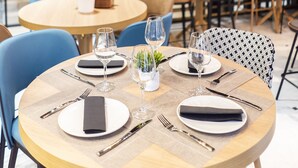 Un restaurante con mesas redondas dispuestas para comer, que cuenta con vasos transparentes y servilletas.