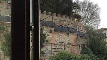 Una pared de piedra con una escalera que sube hacia un edificio.