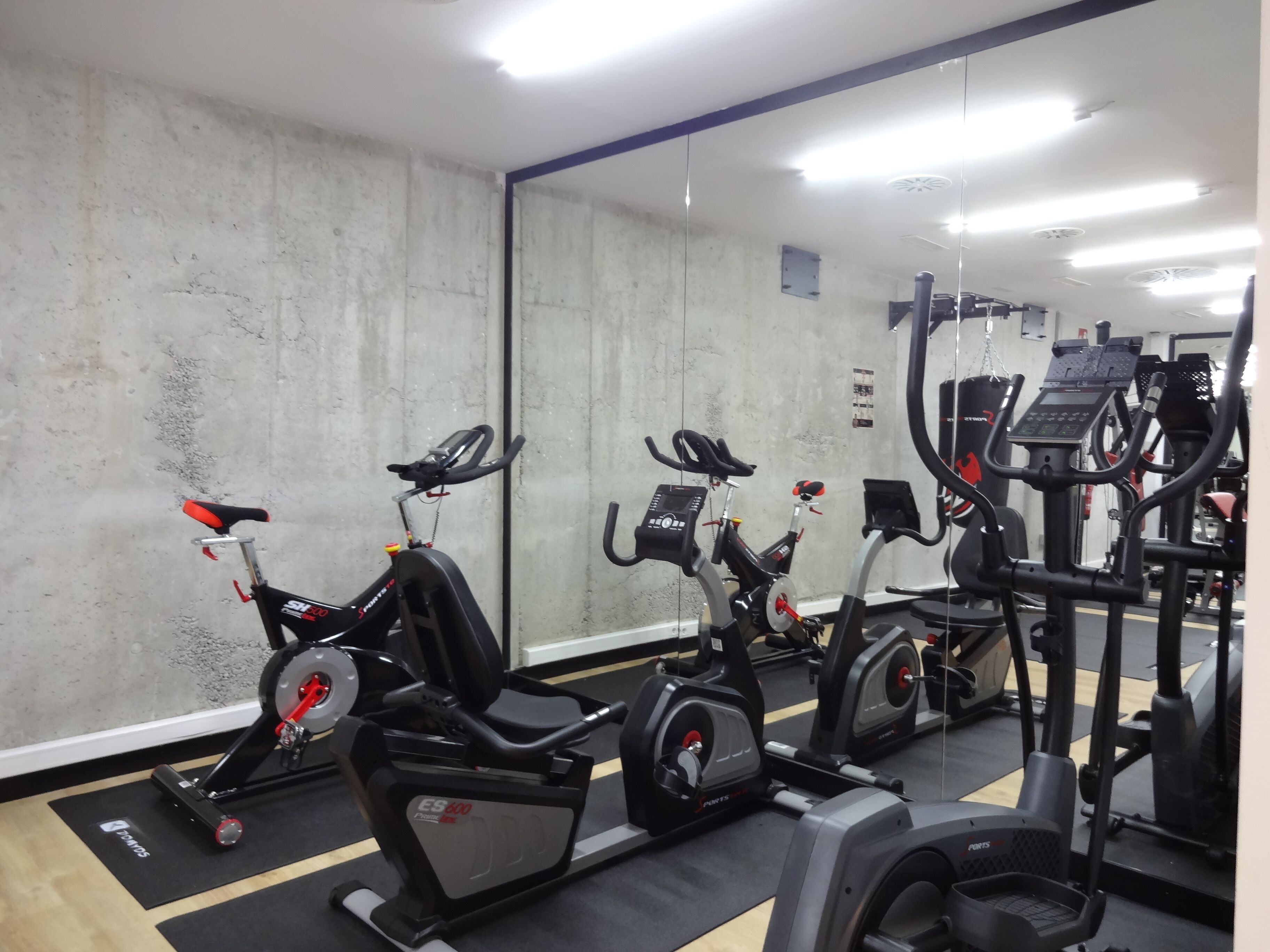 A gym with stationary bikes, a treadmill, and a mirrored wall.