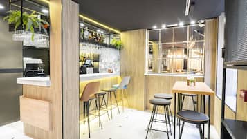 Un moderno espacio de bar con detalles de madera, taburetes y una barra con cristalería.