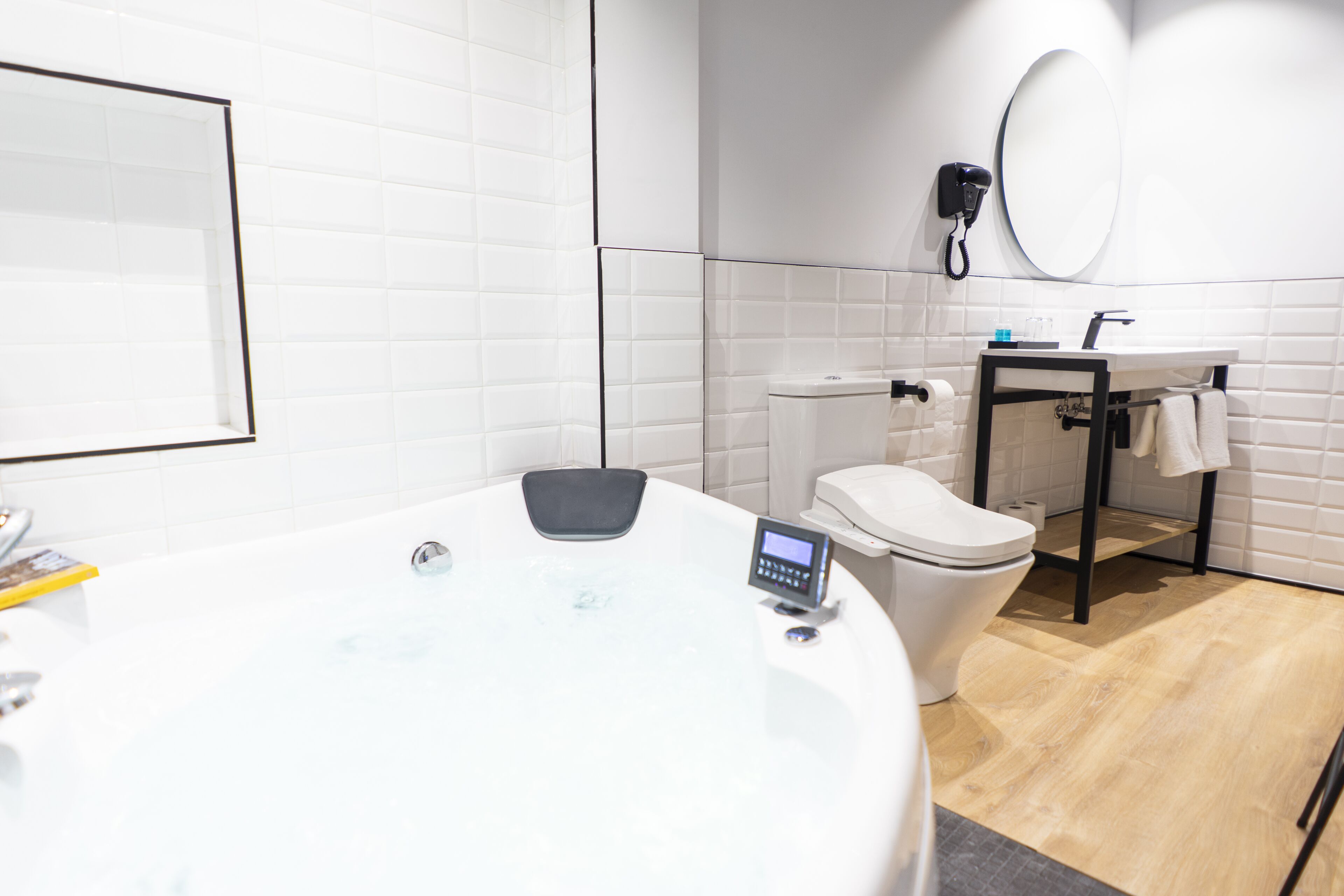 Ein modernes Badezimmer mit einer großen Badewanne, einer Toilette, einem Waschbecken und einem Spiegel.