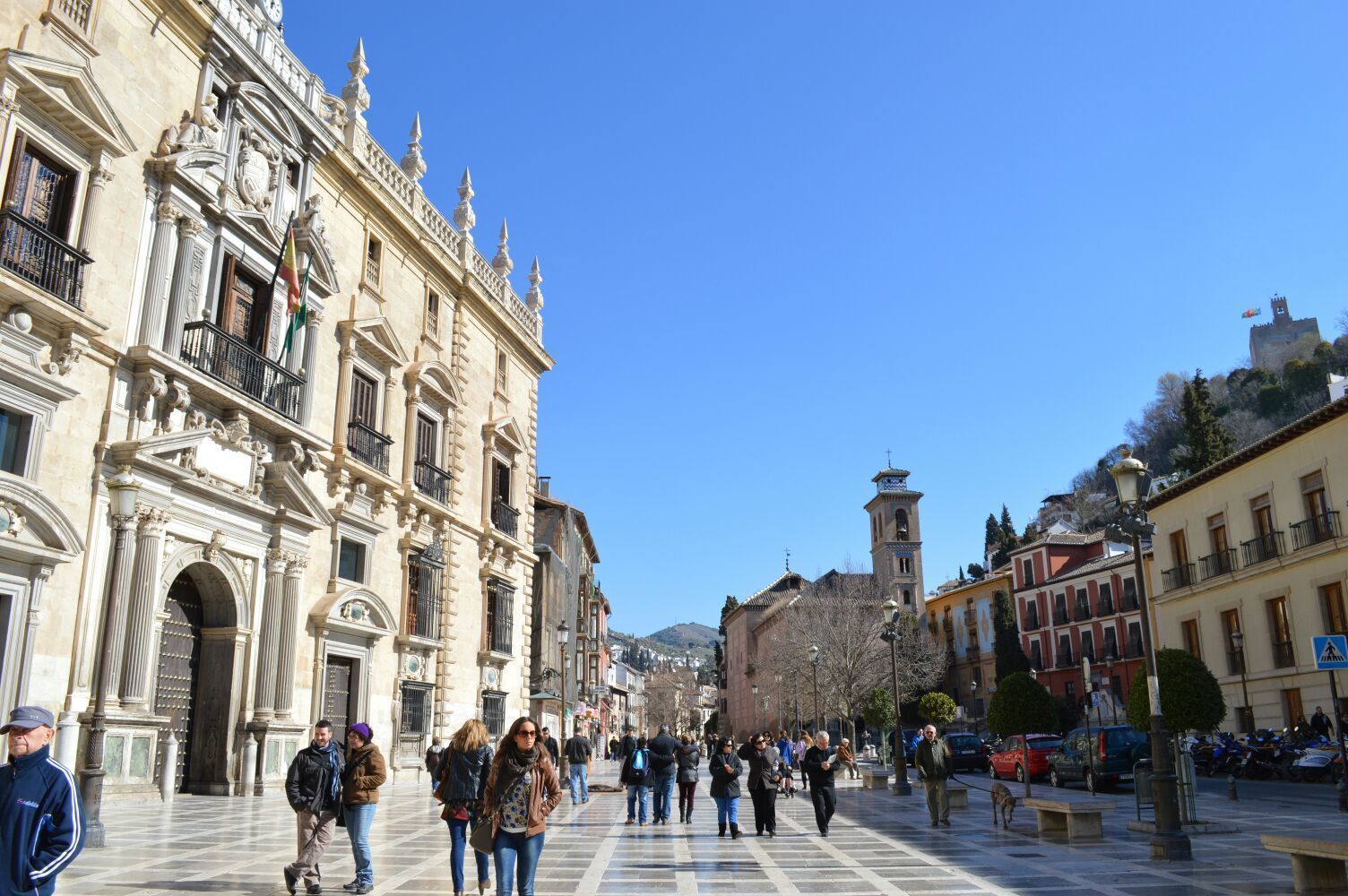 A historic square with ornate architecture, a prominent church, and a clear blue sky.