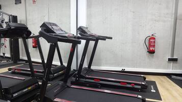 A gym with treadmills, exercise equipment, and a fire extinguisher on the wall.