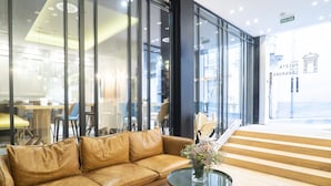 Un interior moderno con un sofá de cuero, una mesa de centro de vidrio y una escalera que lleva a un espacio exterior.