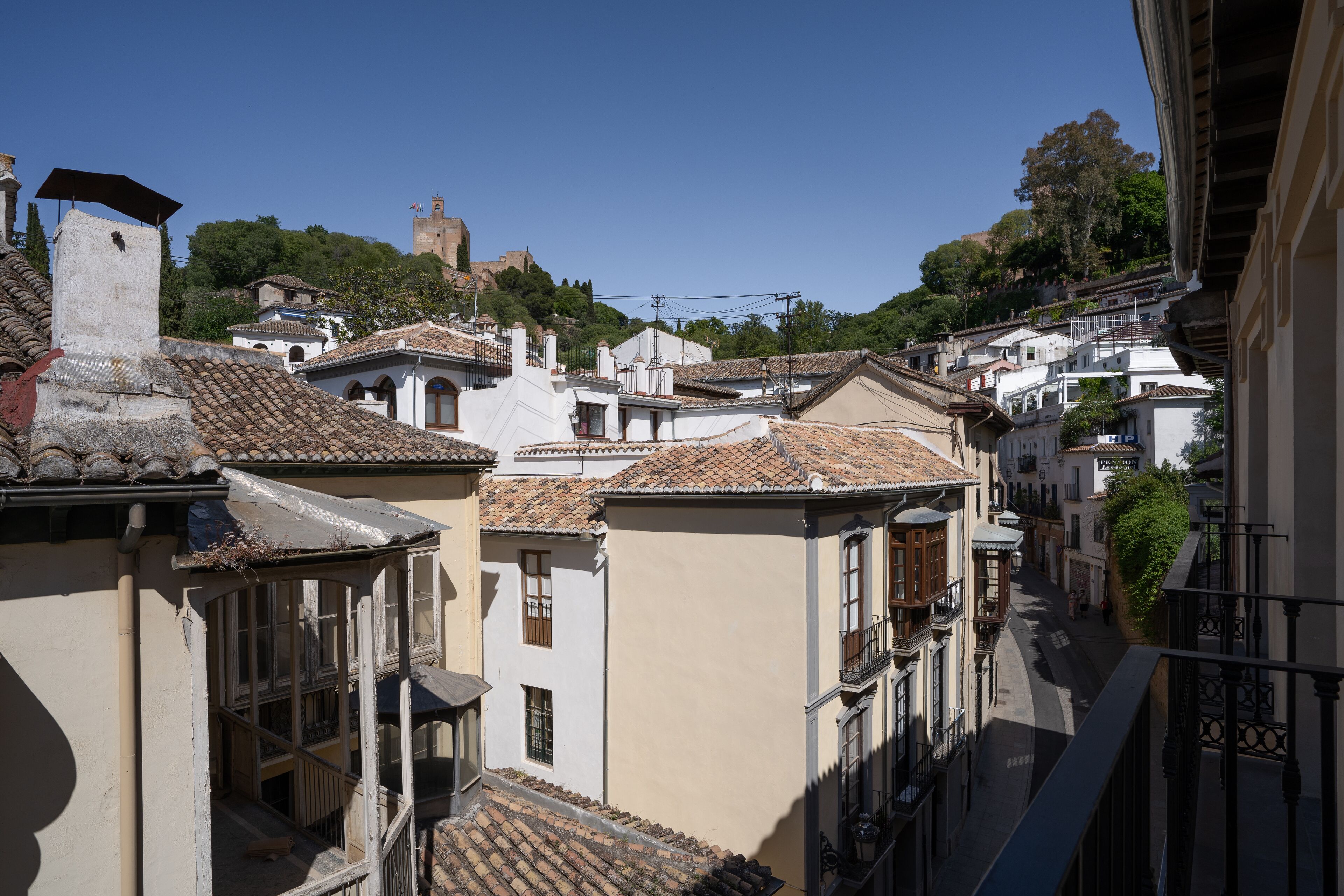 Una calle estrecha con arquitectura tradicional, incluyendo techos de tejas de barro y balcones.