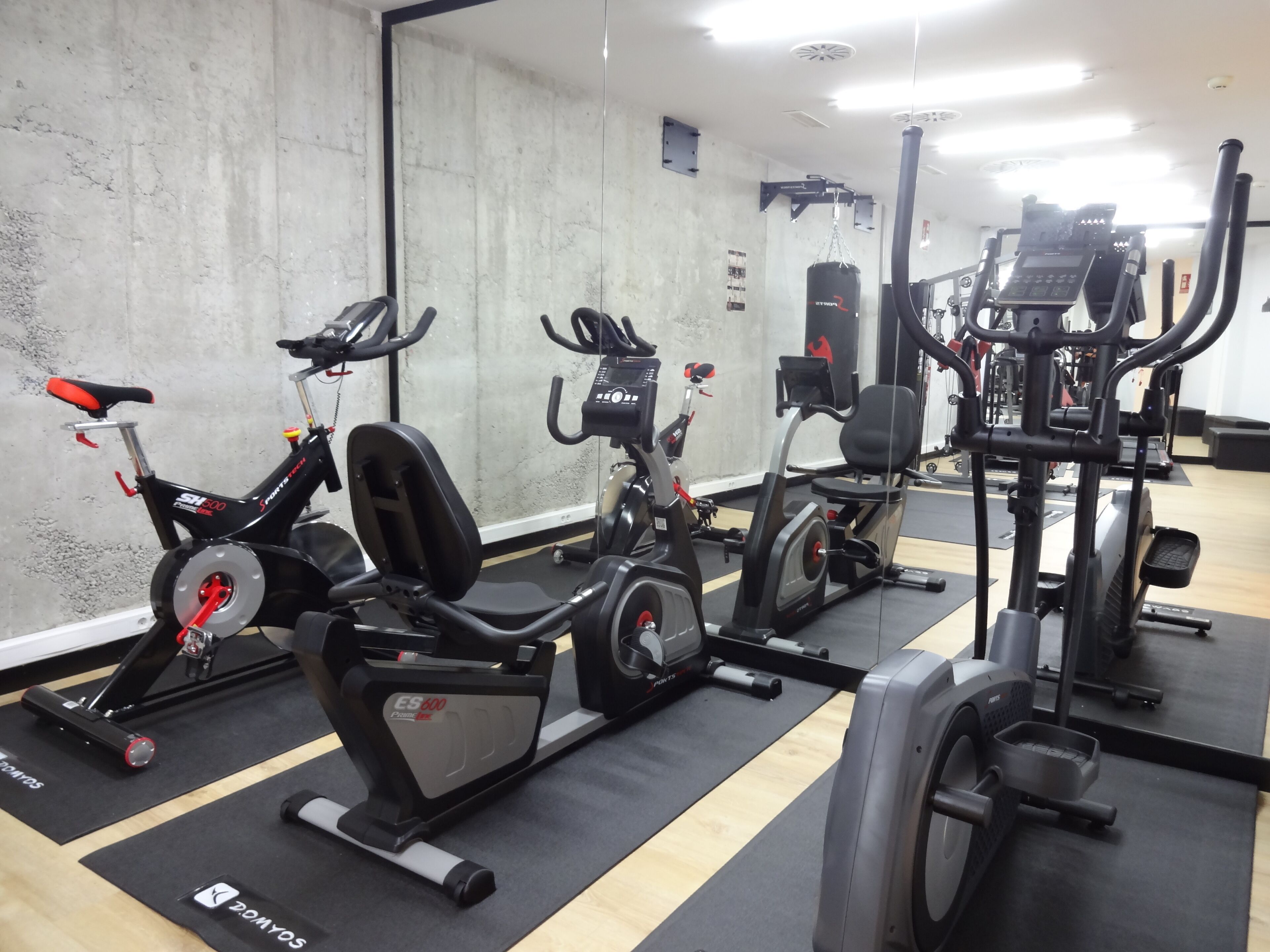 Un gimnasio con bicicletas estáticas, elípticas y máquinas de pesas.