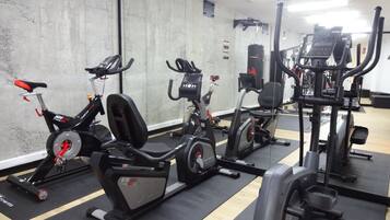 Un gimnasio con bicicletas estáticas, elípticas y máquinas de pesas.