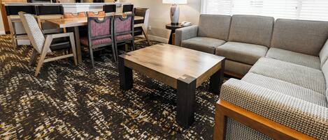 Ein modernes Wohnzimmer mit einer Couch, einem Couchtisch und einem Essbereich mit Stühlen und einem Tisch.