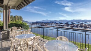Terraza con mobiliario exterior con vistas a un puerto deportivo con barcos y montañas al fondo.