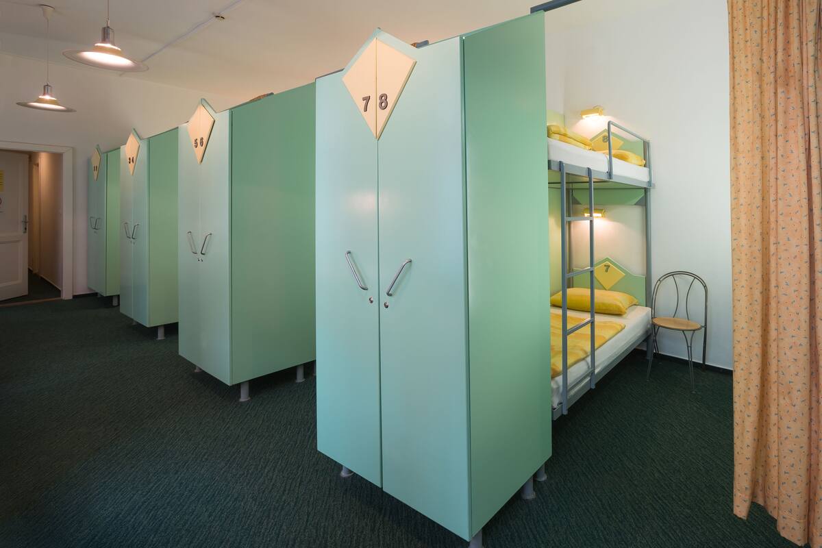 A row of bunk beds with a bunk on each side, a chair, and a door with a number on it.