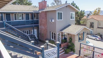A two-story building with a balcony, a staircase, and a car parked in front.