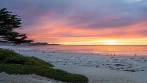 A beach with a sunset, clear sky, and calm sea.