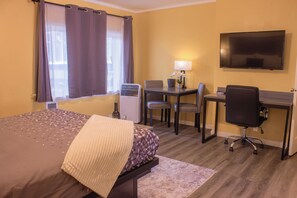 A hotel room with a bed, desk, chair, television, and a window with curtains. - Carmel Wayfarer Inn (Carmel)