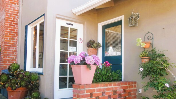 A building entrance with a check-in desk, a door marked 'OFFICE,' and potted plants.