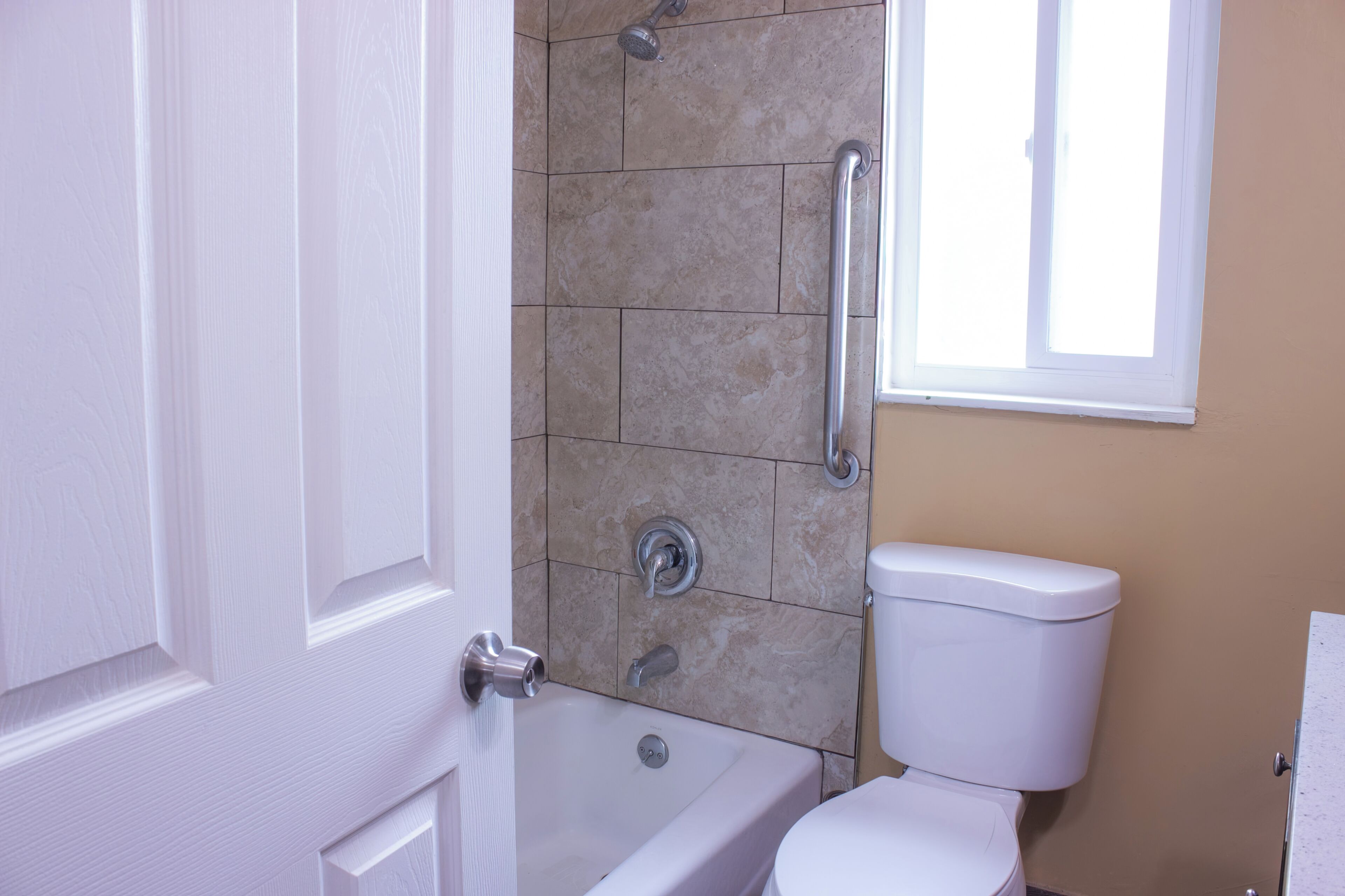A bathroom with a bathtub, toilet, and shower area.