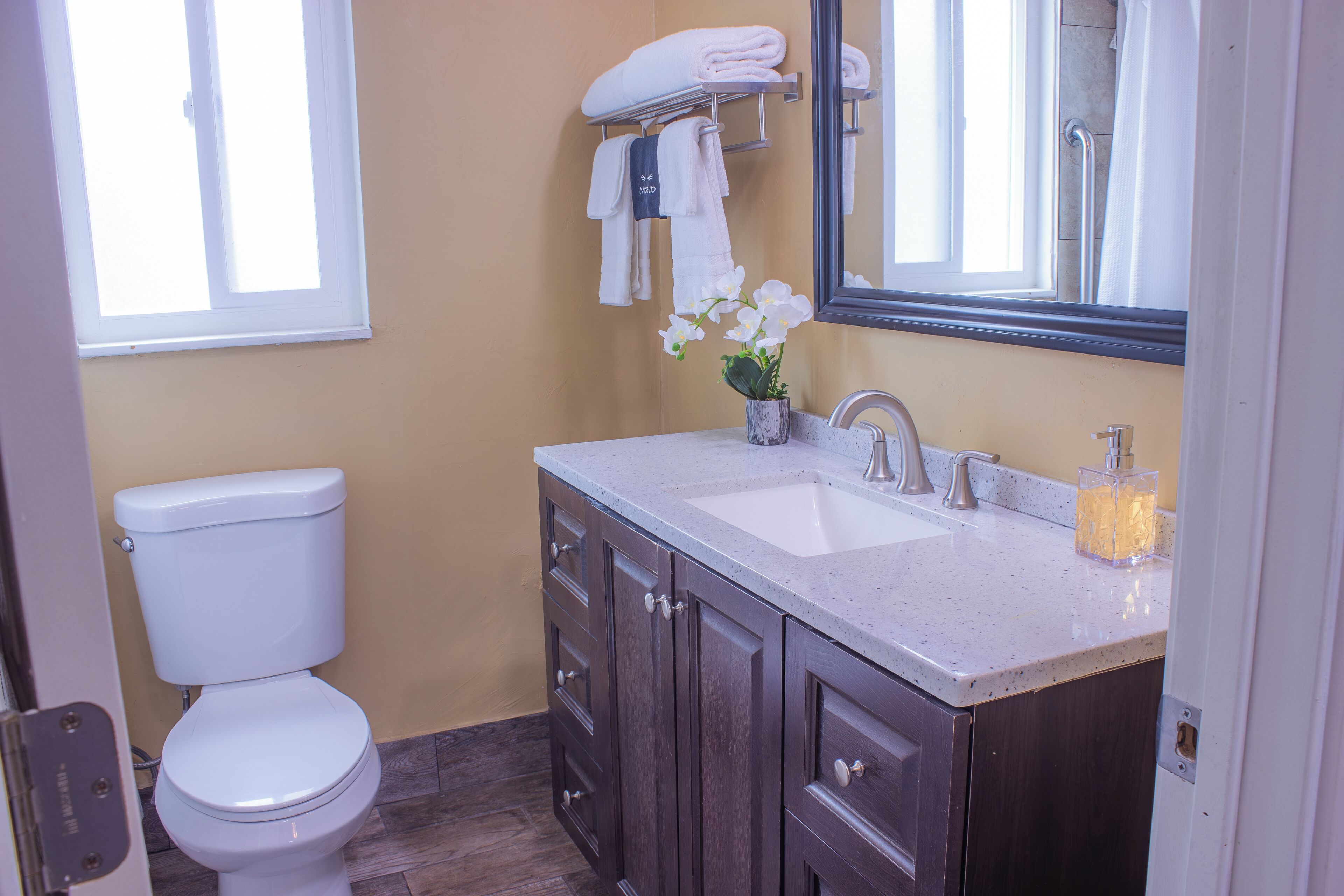 A bathroom with a toilet, a sink, a mirror, and a towel rack.