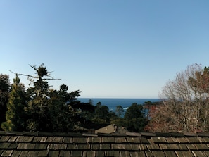A view from a rooftop with a wooden shingled roof, overlooking a coastal landscape with trees and a clear sky. - Carmel Wayfarer Inn (Carmel)