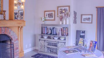A cozy room with a fireplace, a coffee station, and various framed pictures on the walls.
