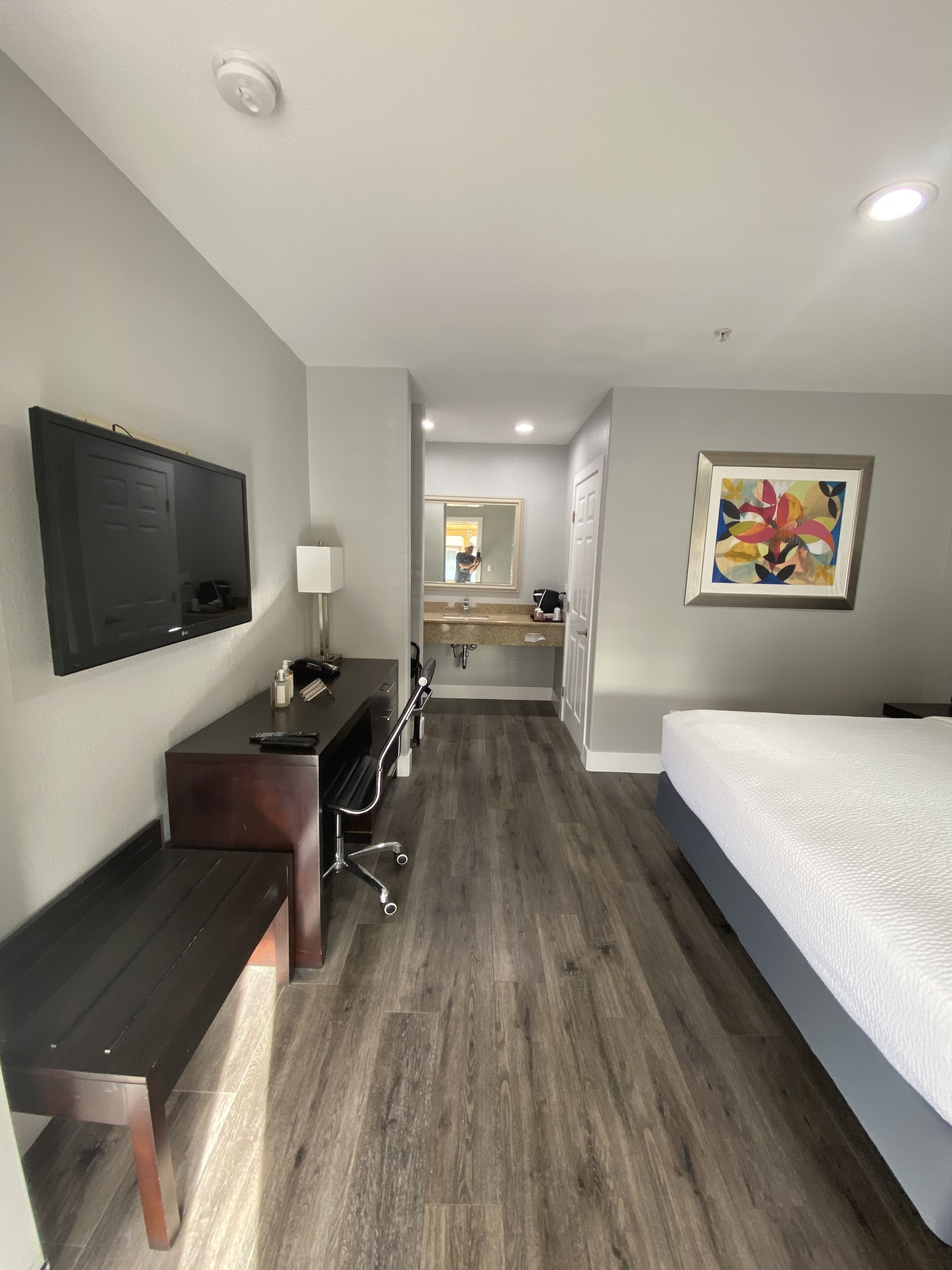 A hotel room with a bed, desk, chair, and a television.