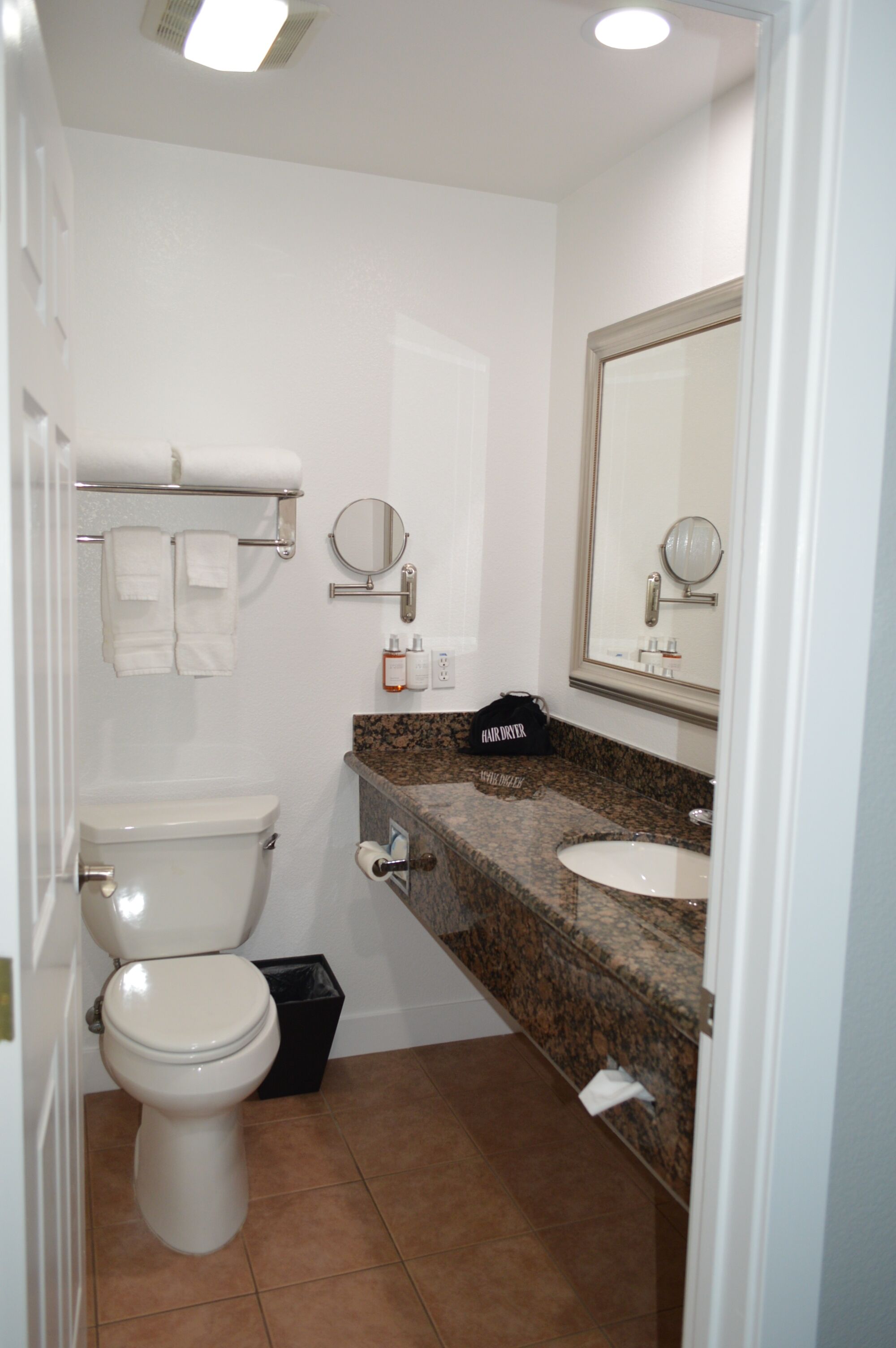 A bathroom with a toilet, sink, towel rack, and mirrors.