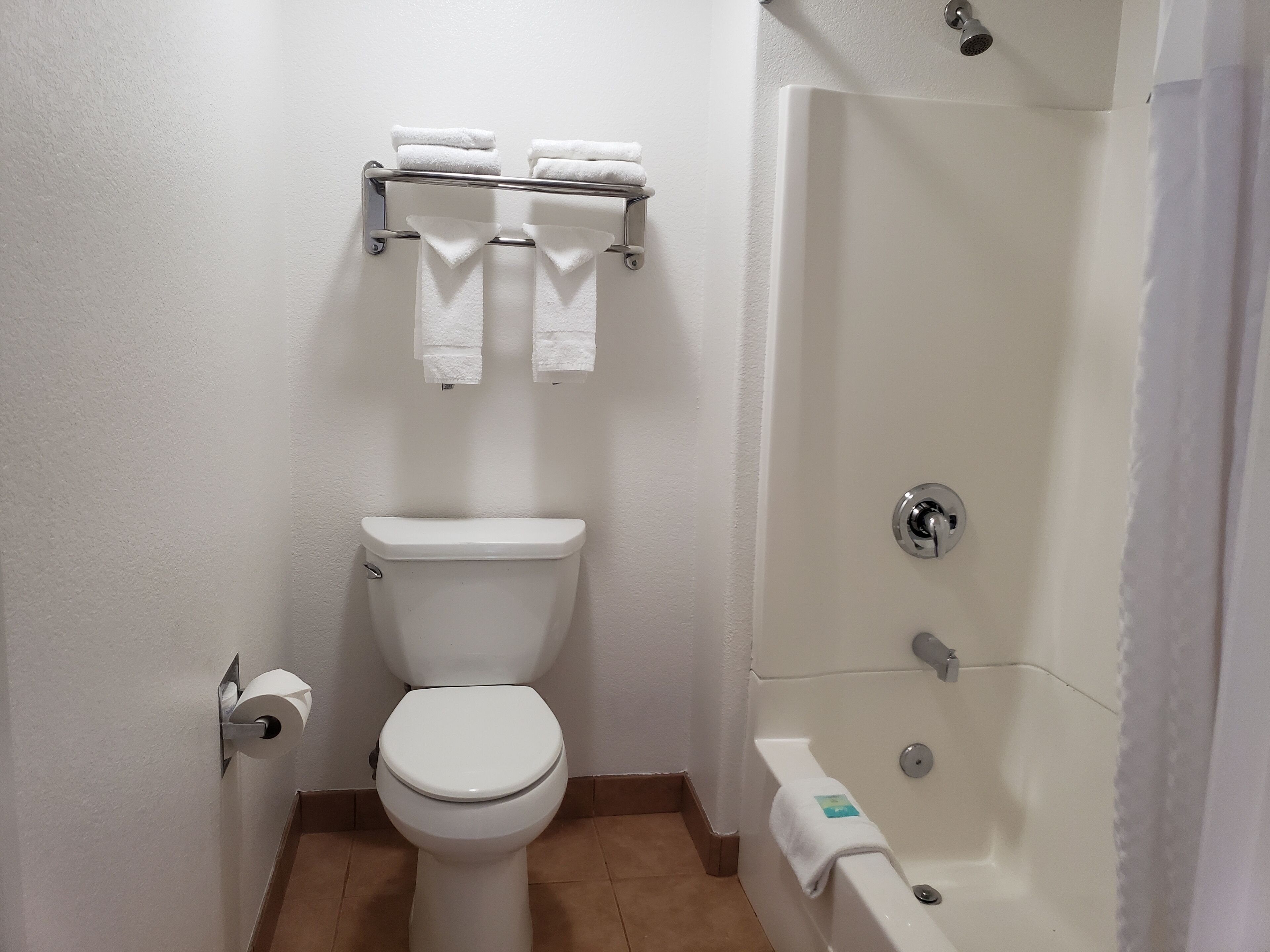 Un baño con inodoro, toallero con toallas y bañera.