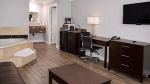 Habitació d'hotel amb un llit gran, escriptori, cadira, televisió i bany.