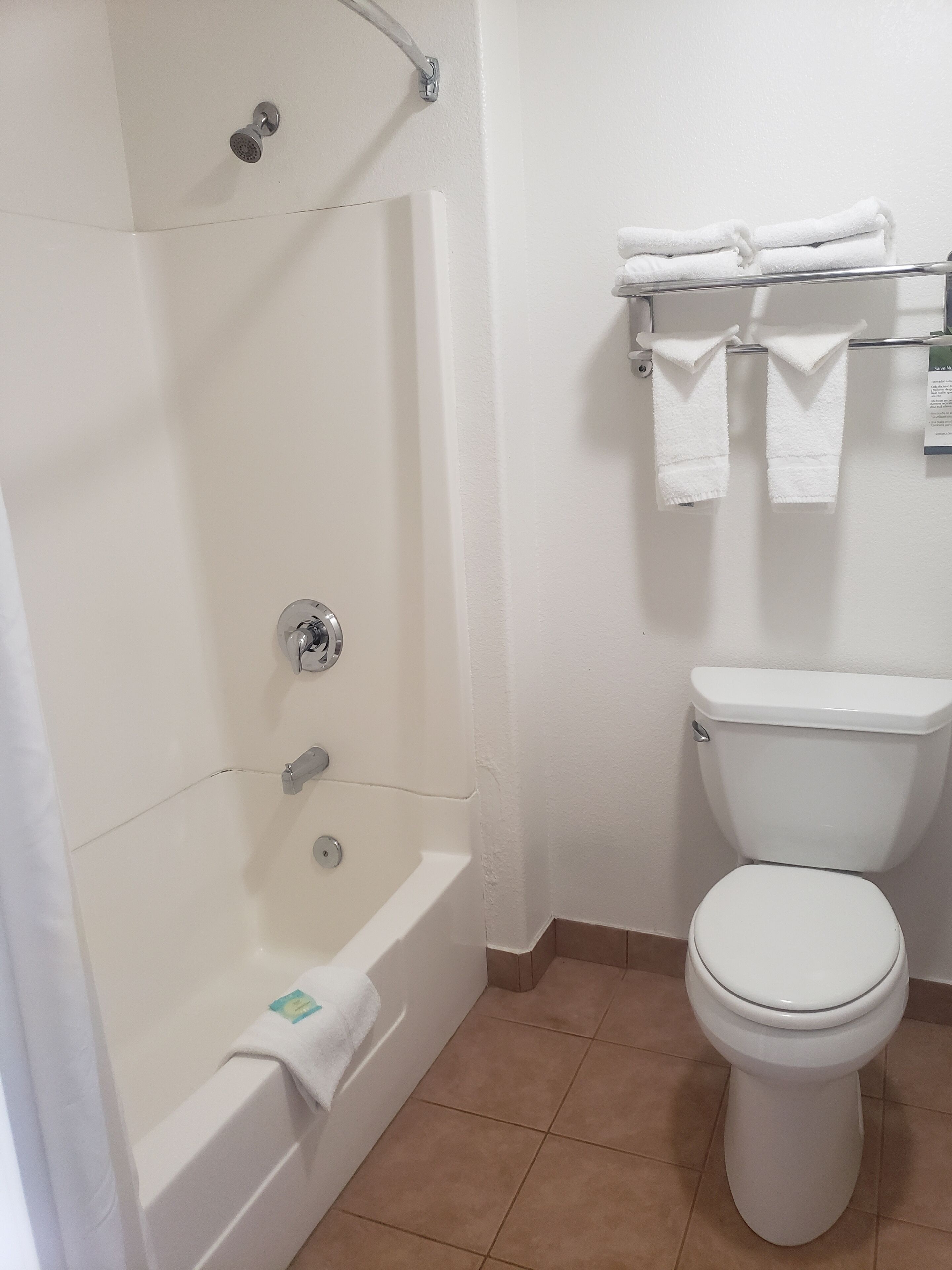 A bathroom with a bathtub, toilet, and towel rack.