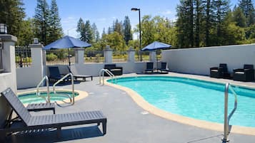 Een buitenzwembad, parasols bij het zwembad en ligstoelen