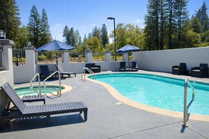 Una piscina al aire libre, sombrillas, sillones reclinables de piscina