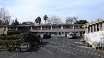 A motel with multiple parking spaces, a covered parking area, and a mural on the side.