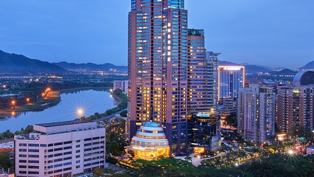 Un hotel de gran altura con un llamativo letrero de 'Four Points', rodeado de otros edificios y un cuerpo de agua al fondo.