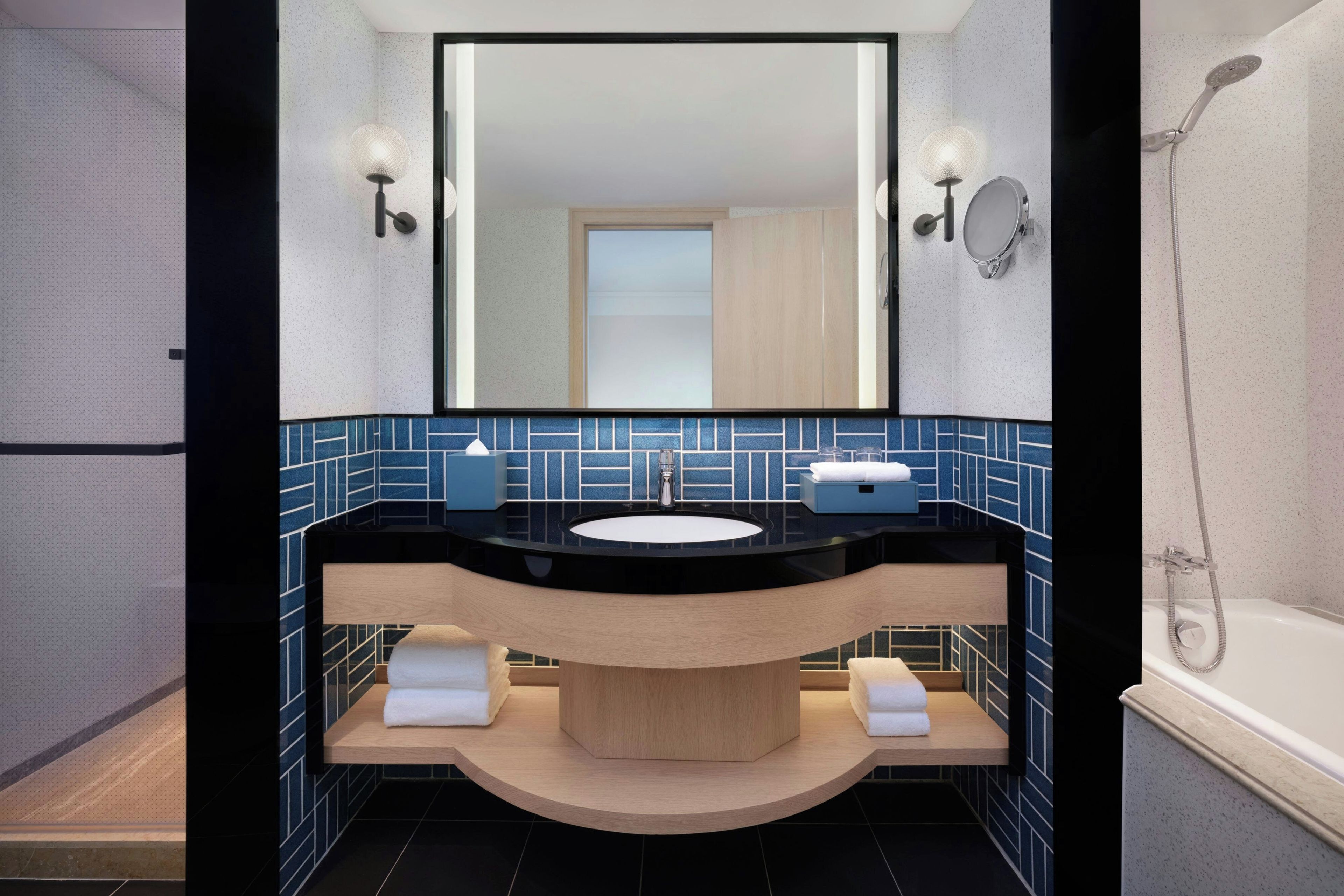 A modern bathroom with a large mirror, a sink, and a shower.