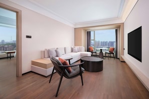 A modern living room with a sectional sofa, a coffee table, and a flat-screen TV. - Four Points by Sheraton Shenzhen (Shenzhen)