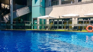 A swimming pool with a lifebuoy, outdoor seating, and a staircase.