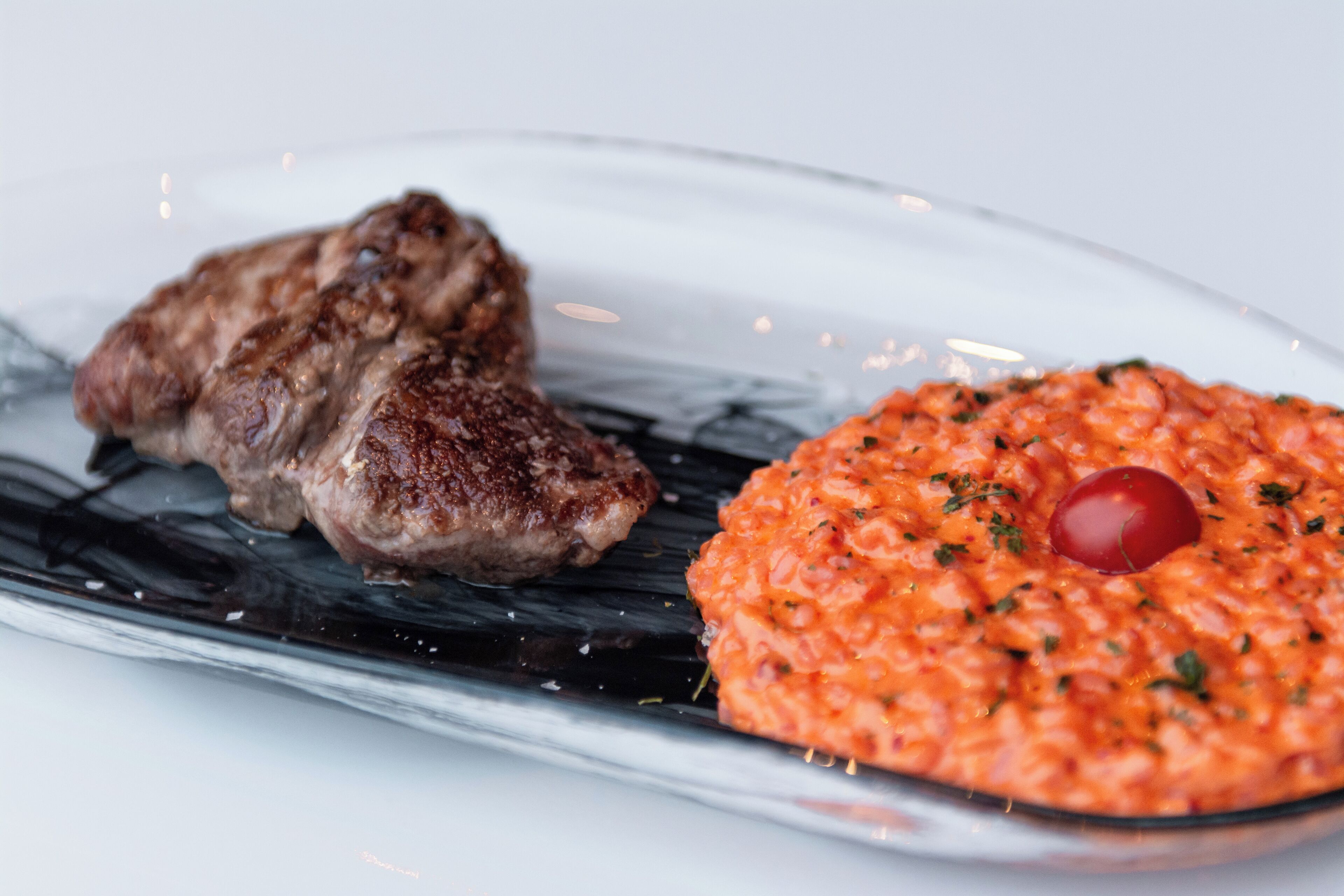 Un plato con carne a la parrilla y un guiso de tomate.