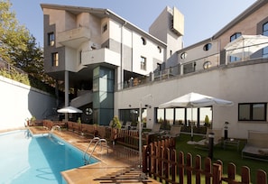 A modern hotel with a swimming pool, outdoor seating, and a well-maintained garden. - Hotel Badajoz Center (Badajoz)