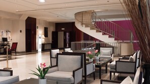 A spacious lobby with a modern staircase, comfortable seating areas, and a reception desk.