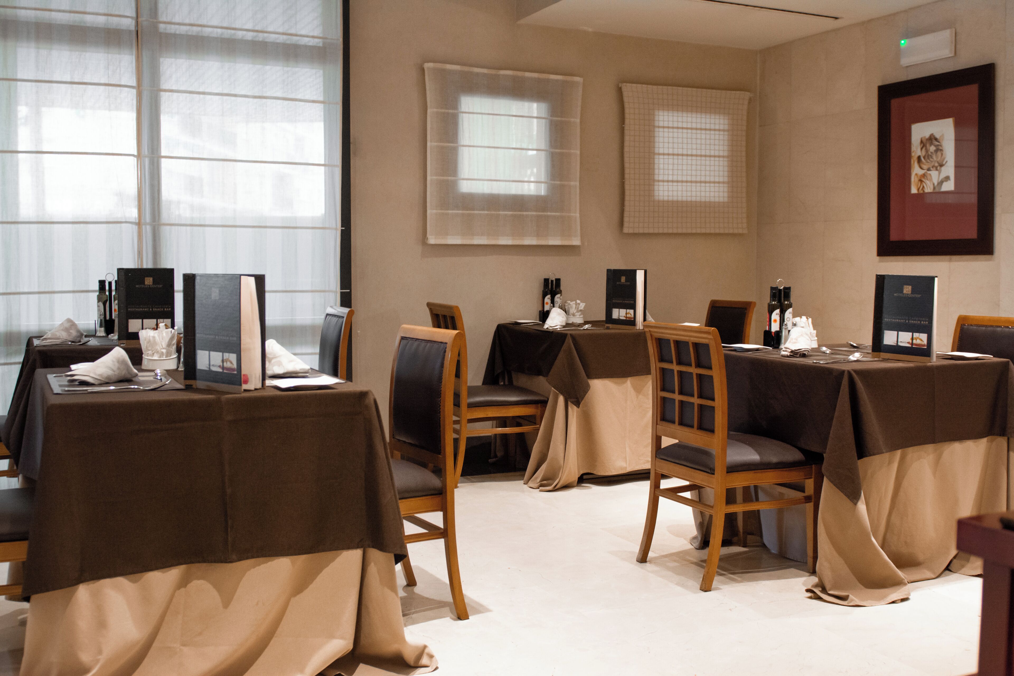 A conference room with tables, chairs, and a large window with blinds.