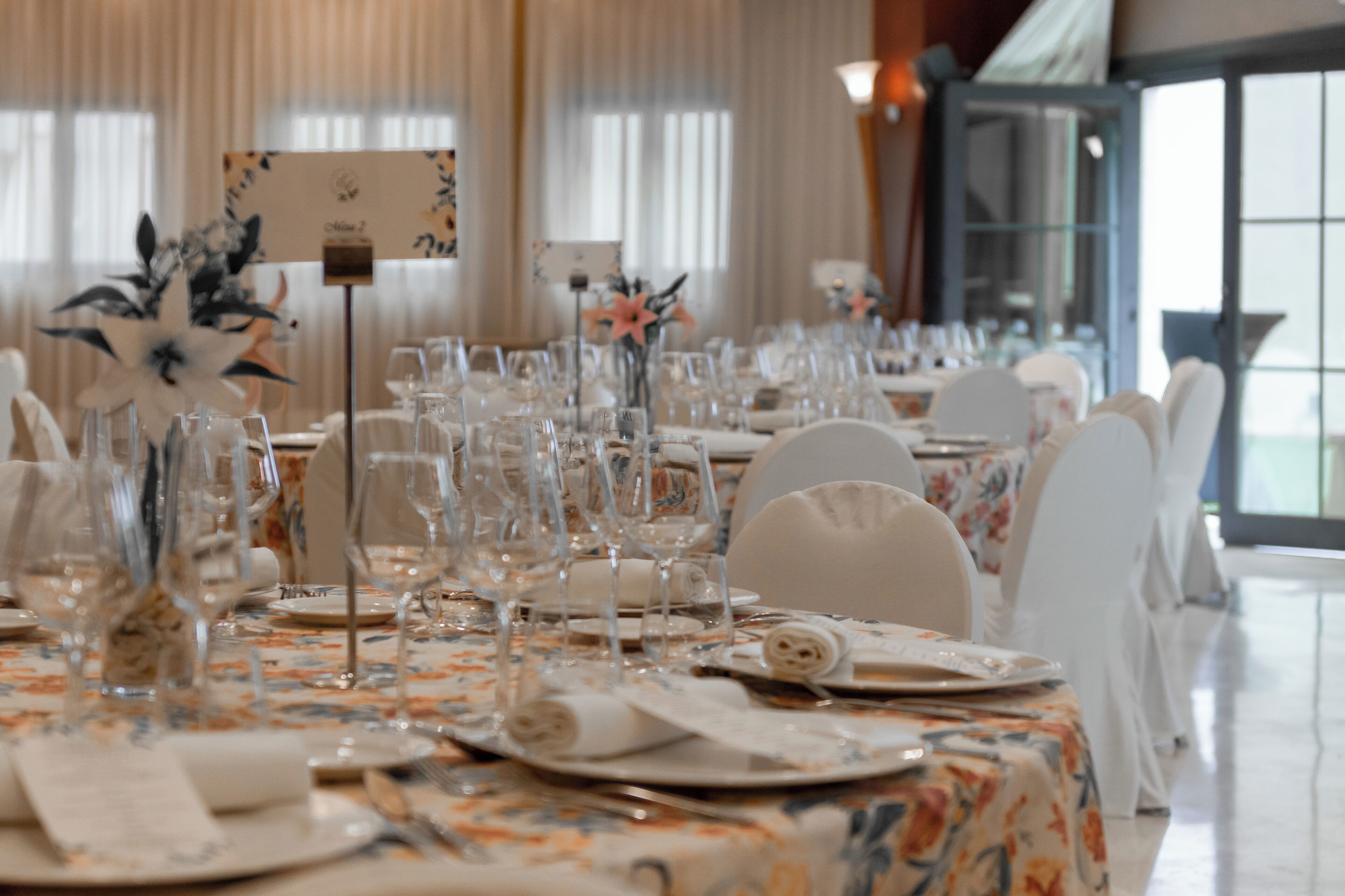 A banquet table set with glassware, plates, and napkins, with floral centerpieces and a sign indicating the table number.