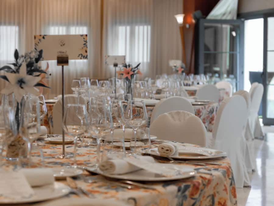A banquet table set with glassware, plates, and napkins, with floral centerpieces and a sign indicating the table number.