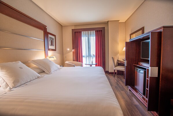 A hotel room with a large bed, two bedside tables, a desk, a chair, and a television. - Hotel Badajoz Center (Badajoz)