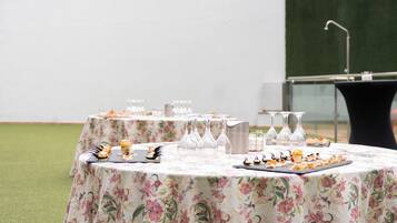 Una mesa dispuesta con mantel floral, copas transparentes y una variedad de aperitivos.
