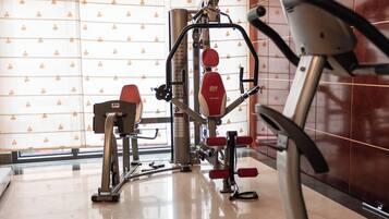Een sportschool met trainingsapparatuur, een spiegelwand en een vloer met patroon.