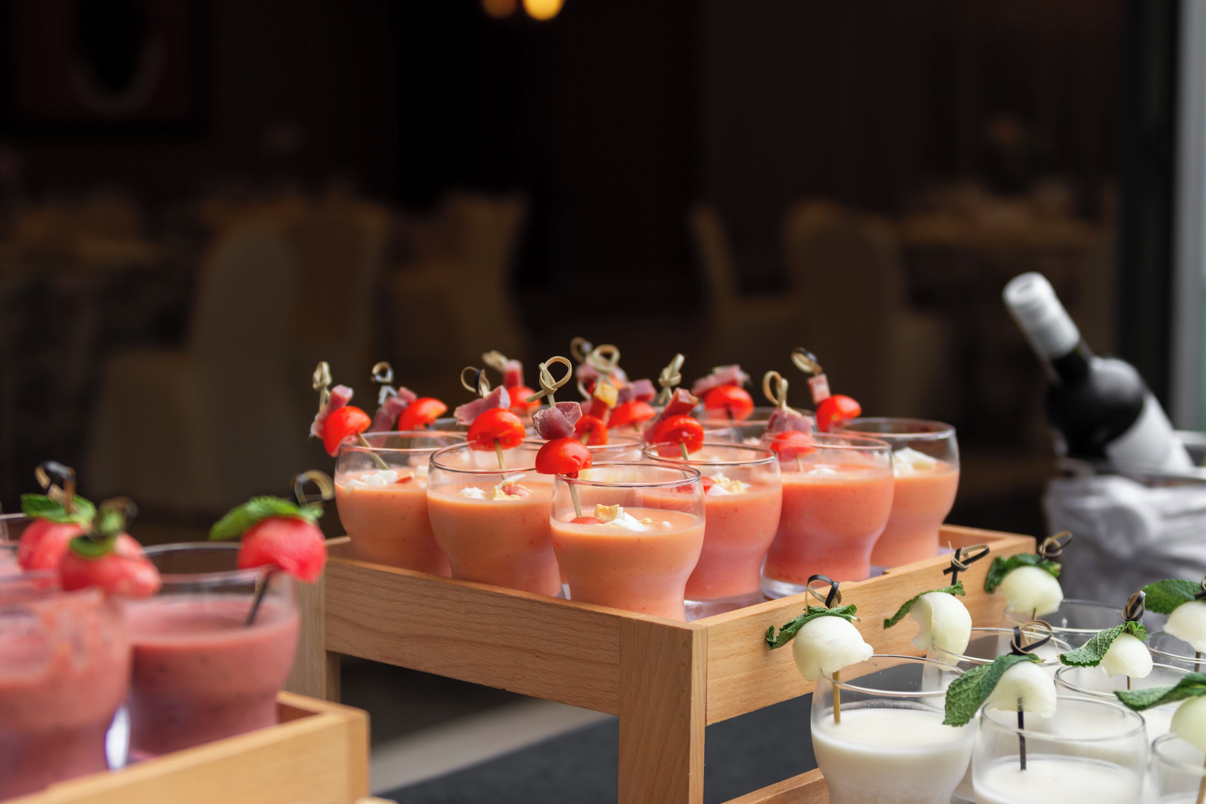 Una bandeja con bebidas adornadas con fruta, probablemente batidos o cócteles, sobre una mesa de madera.