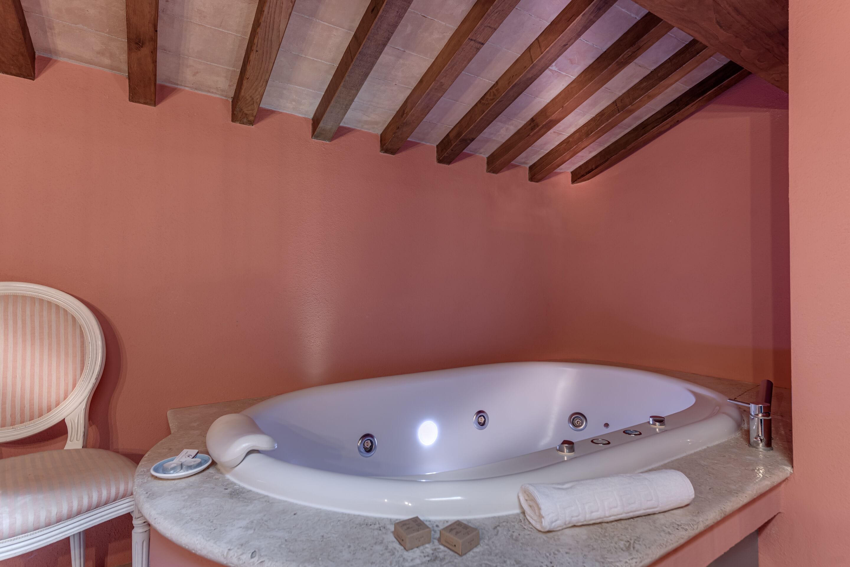 Un baño con una bañera independiente, una silla y una toalla sobre el mostrador.
