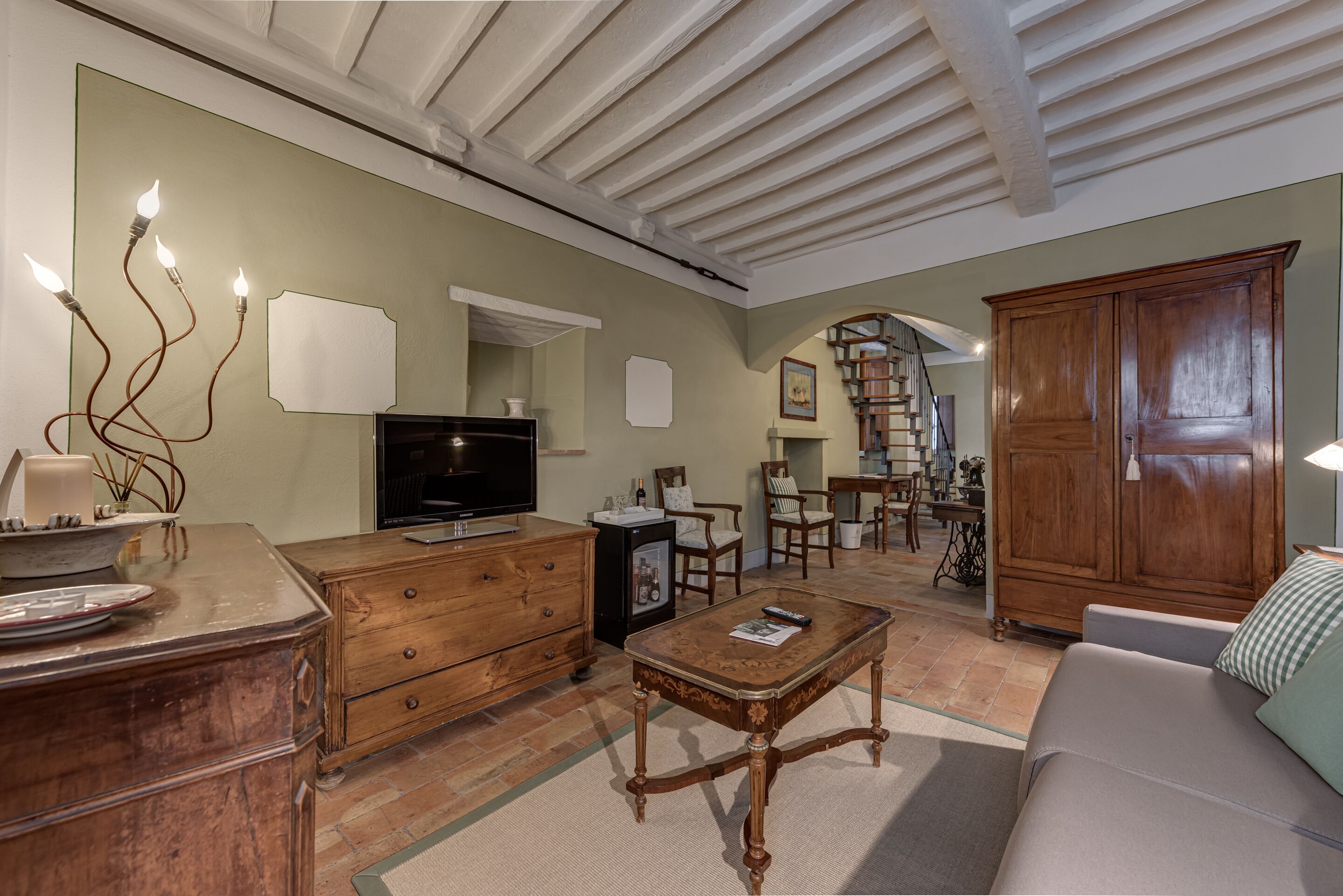 A living room with a television, wooden furniture, a fireplace, and a staircase leading to another level.