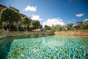 Ein klares Schwimmbecken mit einer Steinmauer und einer Holzbrücke.